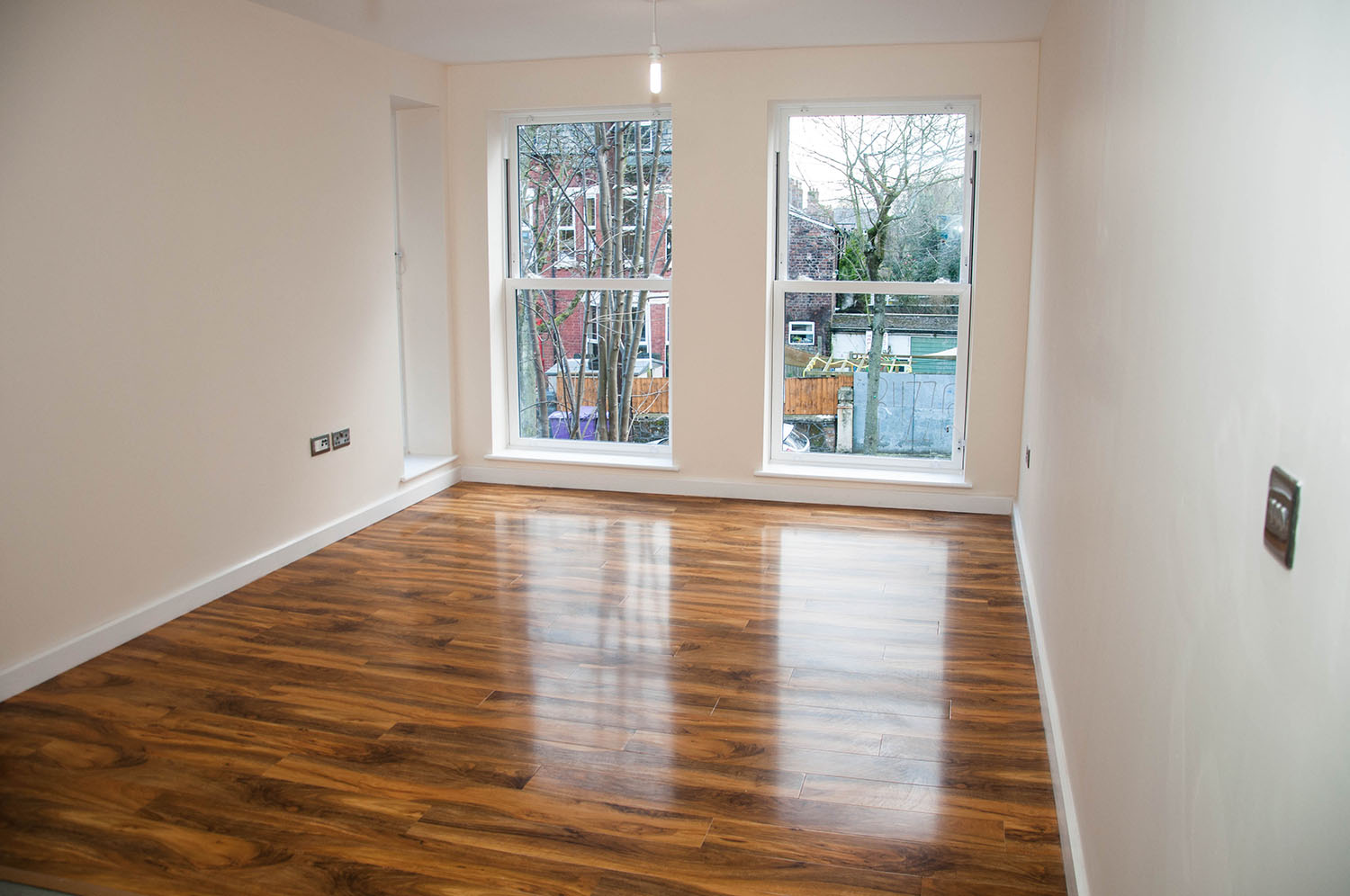 Empty bedroom with glossy wooden floors and 2 windows