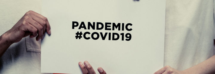 Hands holding a sign that says 'Pandemic #covid19'