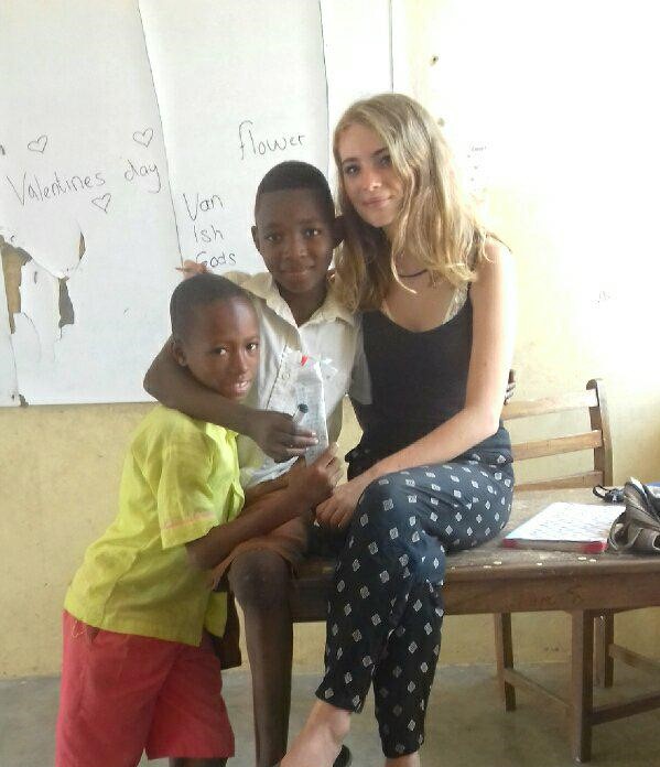 A woman with her arms around two children in a classroom
