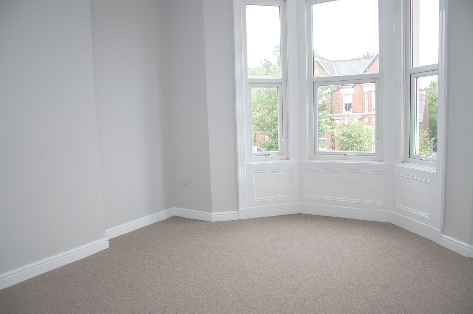 Empty living room with bay windows and a beige carpet
